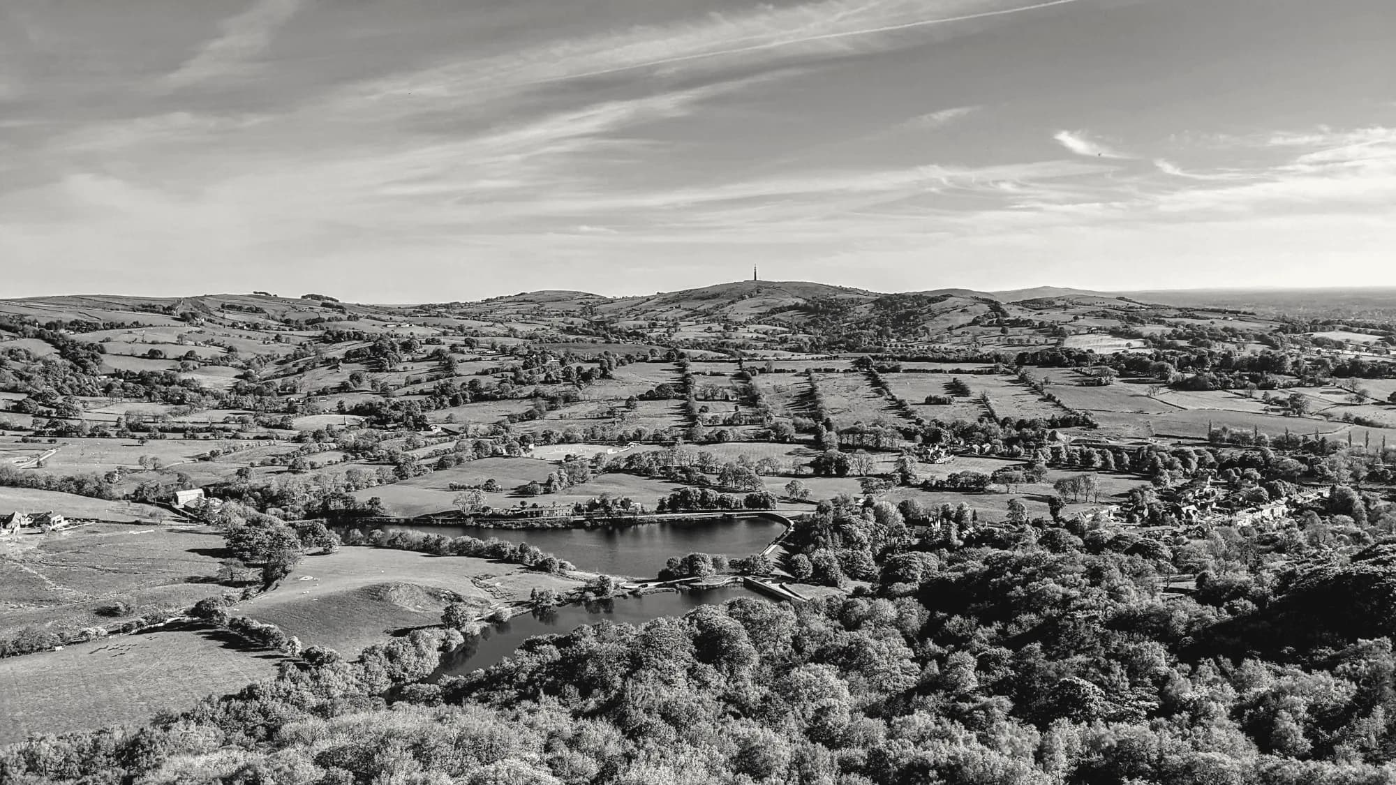 Patchwork fields and woodland around a lake in the Cheshire countryside