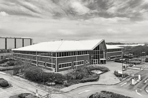 A two-storey brick and glass office building on a landscaped business park